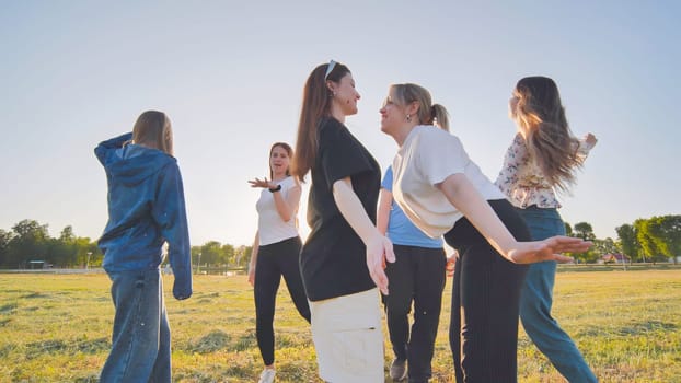 Funny jolly friends dancing in the city meadow in the evening