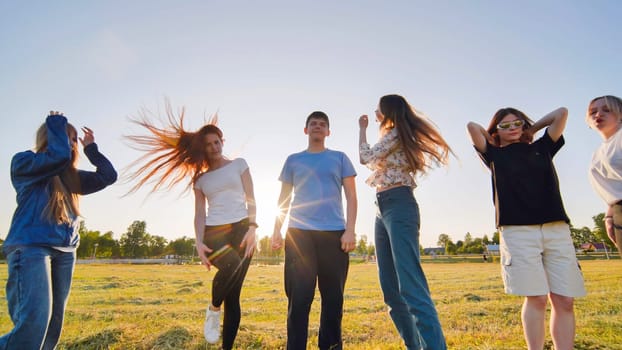 Funny jolly friends dancing in the city meadow in the evening