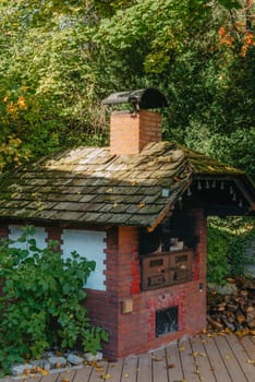 An Old Stove And Firewood For It In The Yard In The Village. Old Stone Fireplace Outdoors In The Fall. Traditional Brick Oven With Wood For Baking Bread Outdoor In Europe.