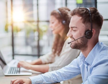 Handsome male customer service agent working in call center office as a telemarketer.