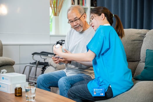 Asian doctor with physician visit senior male patient consult medicine dosage at house in living room, Woman nurse caregiver showing prescription drug to senior man at nursing home, healthcare support