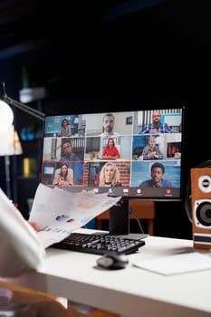 Selective focus on the desktop screen displaying group of people participating in a video conference. Detailed image of professional adults discussing their research in an online meeting.