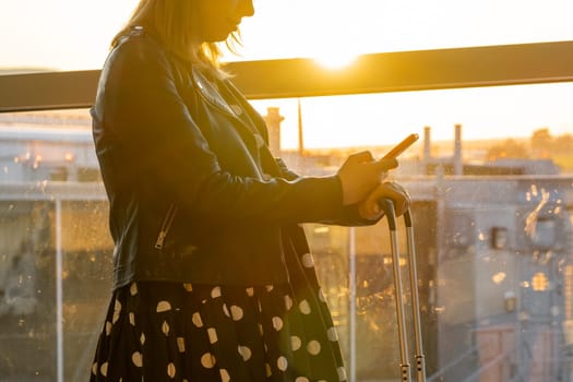 A woman is verifying the departure time at the airport in the sunlight