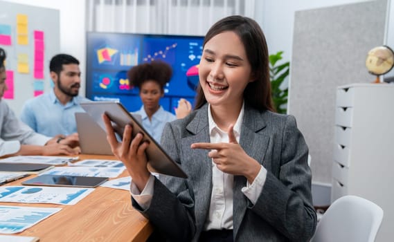 Portrait of happy young asian businesswoman with group of office worker on meeting with screen display business dashboard in background. Confident office lady at team meeting. Concord