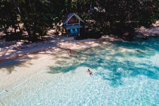 Koh Wai Island Thailand is a tinny tropical Island near Koh Chang. wooden bamboo hut bungalow on the beach. a young couple of men and women swimming in the blue ocean on a tropical Island in Thailand