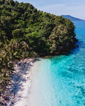 Drone aerial view at Koh Wai Island Trat Thailand. a young couple of men and women walking on a tropical beach with a blue ocean during a luxury vacation in Thailand