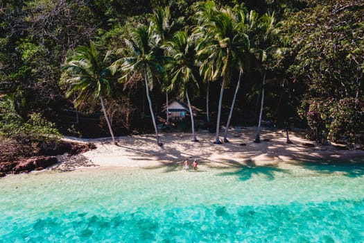 a young couple of men and woman on a tropical Island with a turqouse colored ocean in Thailand, Koh Wai Island Trat