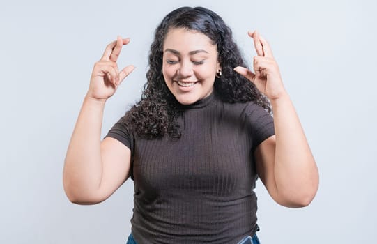 Smiling young woman making a wish with hopeful gesture. Latin girl crossing fingers making a wish