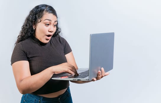 Amazed latin woman using laptop isolated. Surprised girl looking at an promotion on laptop screen
