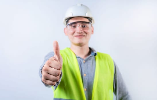 Smiling young engineer gesturing approval with thumb. Cheerful engineer giving thumbs up to the camera isolated