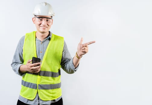 Smiling engineer holding cell phone and pointing an advertisement. Young latin engineer holding phone and pointing at blank space