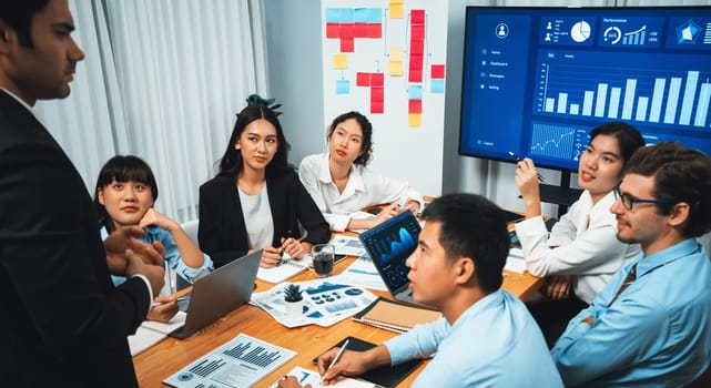 Diverse group of business analyst team analyzing financial data report. Finance data analysis chart and graph dashboard show on TV screen in meeting room for strategic marketing planning. Habiliment