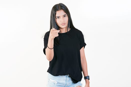 Young girl pointing at you frowning isolated. Serious girl pointing at the camera, isolated