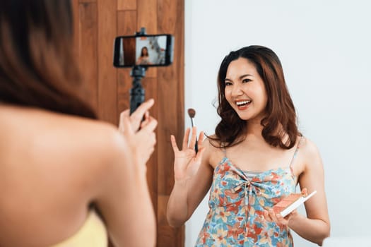 Asian Woman influencer shoot live streaming vlog video review makeup uttermost social media or blog. Happy young girl with cosmetics studio lighting for marketing recording session broadcasting online