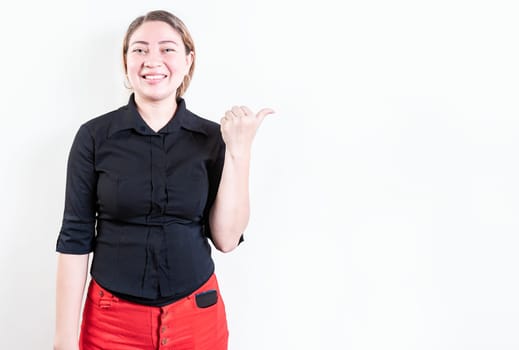 Beautiful young girl pointing to a banner to the side. Happy latin woman pointing a promo isolated. Cheerful latin girl pointing an offer isolated