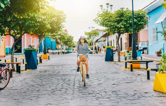 Happy tourist girl riding a bicycle on Calzada street. Young tourist woman riding a bicycle on the streets of Granada, Nicaragua