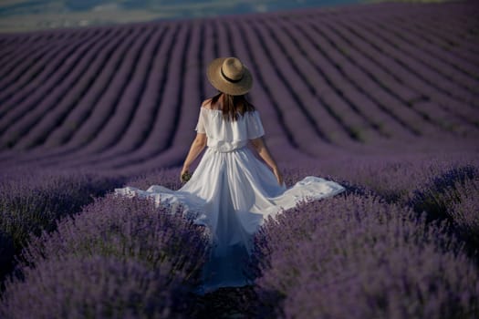 Back view woman lavender sunset. Happy woman in white dress holds lavender bouquet. Aromatherapy concept, lavender oil, photo session in lavender.