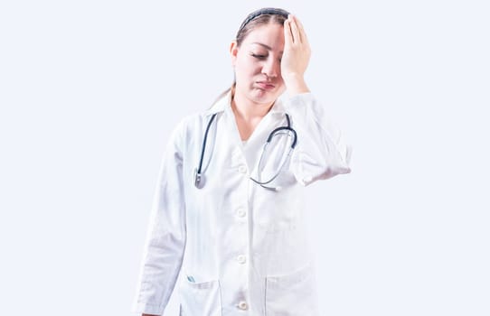 Exhausted female doctor with hand on forehead. Tired young female doctor with hand on forehead isolated