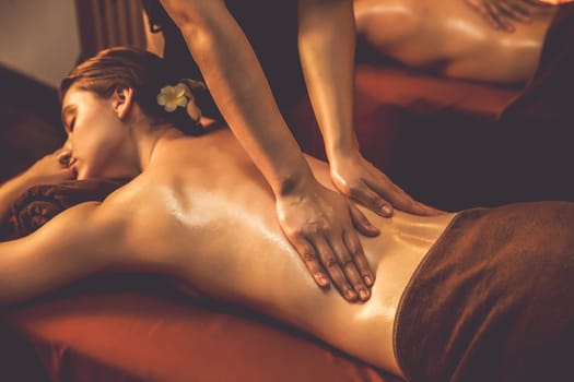 Caucasian woman customer enjoying relaxing anti-stress spa massage and pampering with beauty skin recreation leisure in warm candle lighting ambient salon spa at luxury resort or hotel. Quiescent