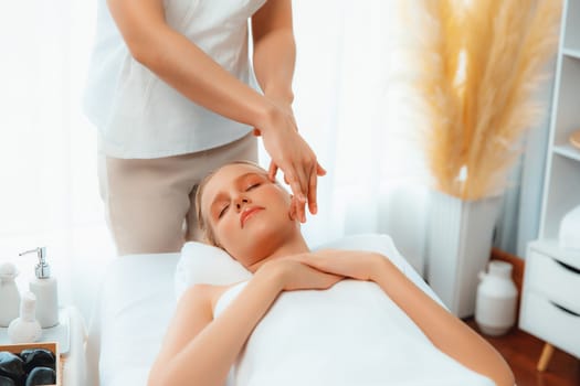 Caucasian woman enjoying relaxing anti-stress head massage and pampering facial beauty skin recreation leisure in dayspa modern light ambient at luxury resort or hotel spa salon. Quiescent