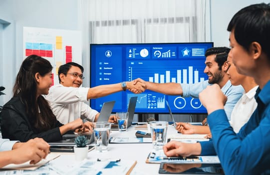 Analyst team leader shake hand with his colleague after successful data analysis meeting using FIntech software power with business intelligence or BI dashboard. Prudent