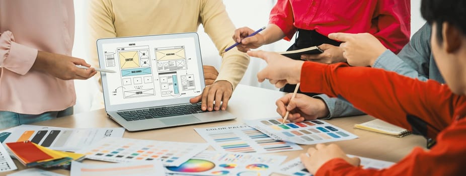 Cropped image of interior designer team discuss the material color while laptop displayed website wireframe designs for mobiles app and website. Creative design and business concept. Variegated.