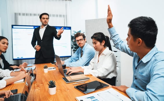 Corporate employee raise hand ask question during project meeting, businessman or manager explaining business task planning schedule with timeline software show on TV screen. Habiliment