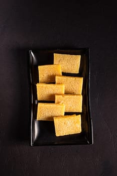 sliced ingredients in a flat black plate on a white background