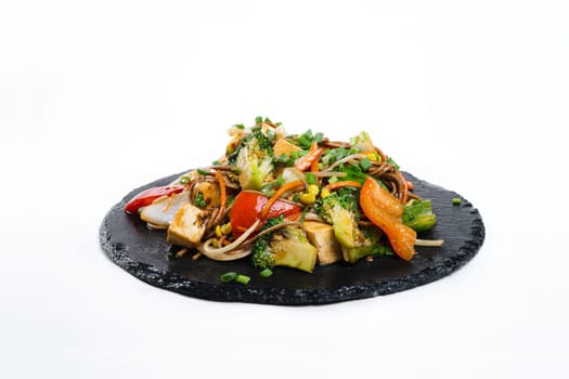 fried assorted vegetables with meat in a flat plate on a white background