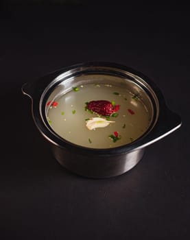 soup broth in an iron plate on a dark background