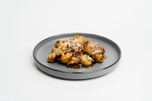 fried chicken nuggets in sauce in a flat plate on a white background