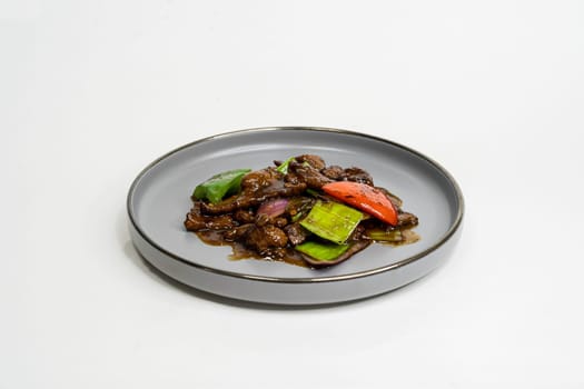 fried assorted vegetables with meat in a flat plate on a white background