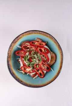 red sweet pepper with onions, tomatoes and vegetables in a plate on a white background