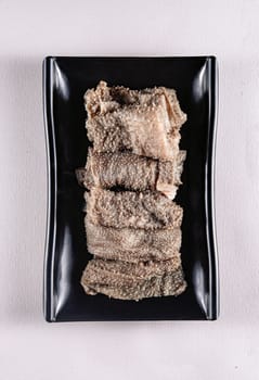 sliced boiled meat on a black plate on a white background