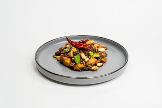 fried assorted vegetables with meat in a flat plate on a white background