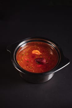 soup broth in an iron plate on a dark background