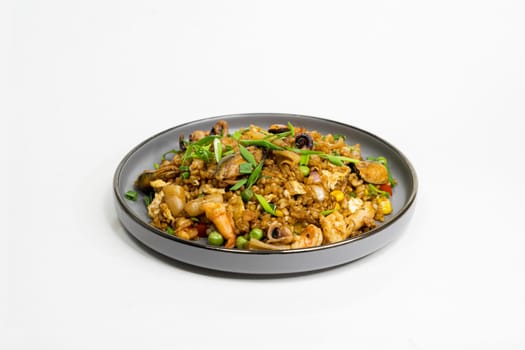 fried noodles with vegetables and meat in a flat plate on a white background