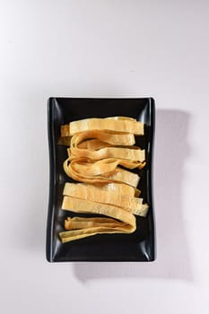 sliced ingredients in a flat black plate on a white background