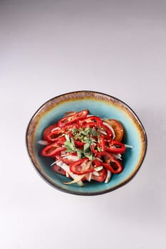 red sweet pepper with onions, tomatoes and vegetables in a plate on a white background