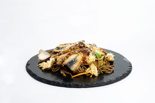 fried noodles with vegetables and meat in a flat plate on a white background