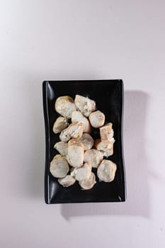 sliced boiled meat on a black plate on a white background