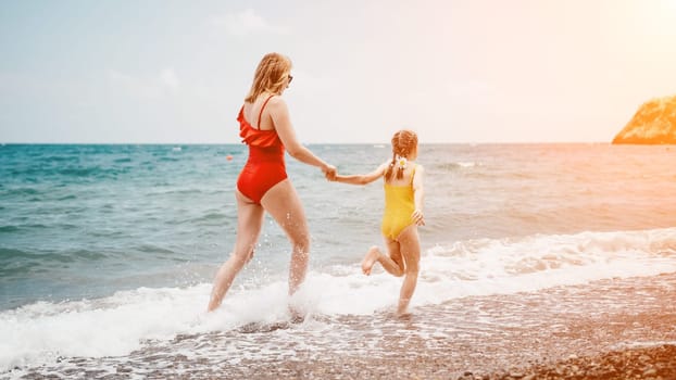 Happy loving family mother and daughter having fun together on the beach. Mum playing with her kid in holiday vacation next to the ocean - Family lifestyle and love concept.