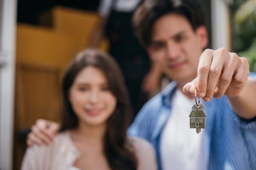 A couple celebrates a successful relocation showing keys while carrying a mattress into their new home. Their happiness marks the joy of moving. Moving Day Concept