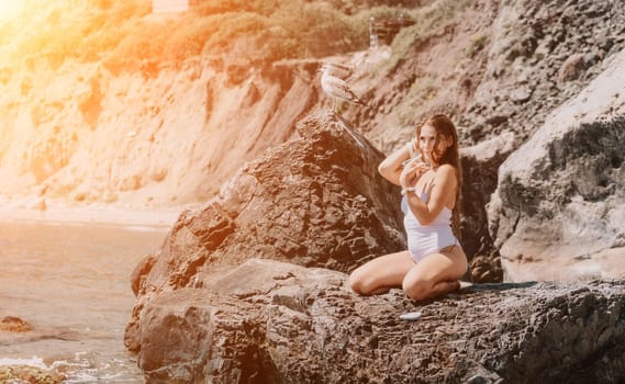 Woman travel sea. Young Happy woman in a long red dress posing on a beach near the sea on background of volcanic rocks, like in Iceland, sharing travel adventure journey