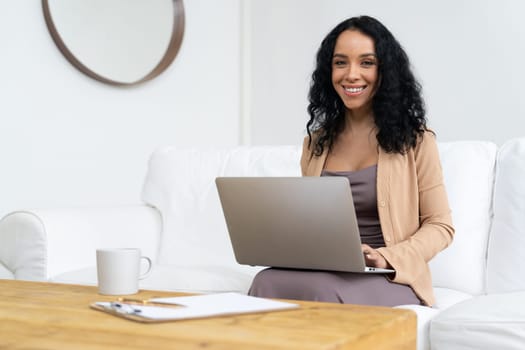 African-American woman using laptop computer for crucial work on internet. Secretary or online content writing working at home.