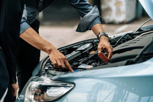 Man help woman fix the car problem. He pop up the car hood to repair the damaged part. uds