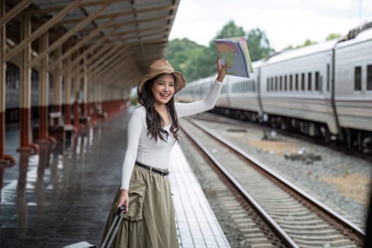 Alone Asian woman traveler with suitcase in train station platform. Summer vacation holiday and travel concept.