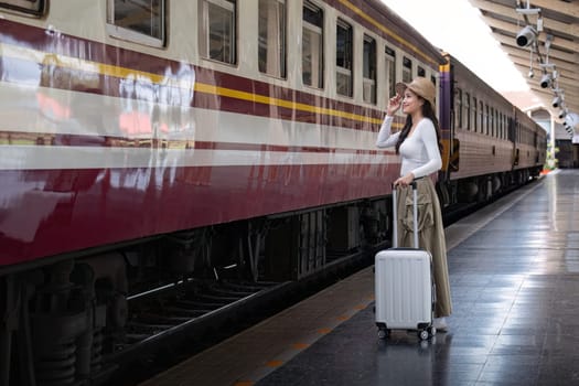 Alone Asian woman traveler with suitcase in train station platform. Summer vacation holiday and travel concept.