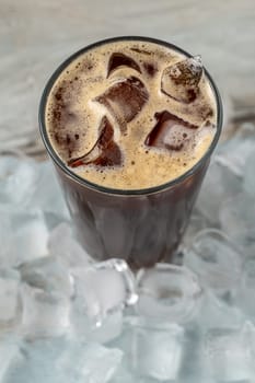 A cup of Iced Americano Coffee with ice cubes placed on a wooden table in a coffee shop. Top view of a glass of coffee.