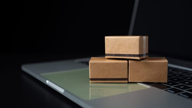 Boxes on a laptop keyboard on dark background. Ideas about online shopping, online shopping is a form of electronic commerce that allows consumers to directly buy goods from seller over the internet.